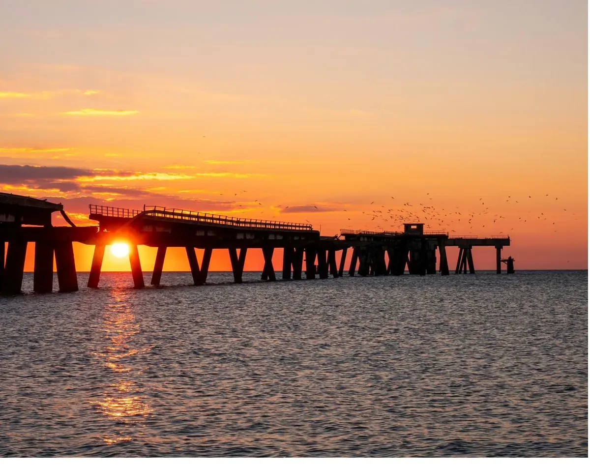 Pontile sul mare di Lamezia Terme al tramonto con cielo arancione
