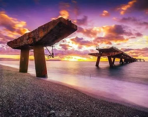 Vecchio pontile sul mare al tramonto con cielo rosato