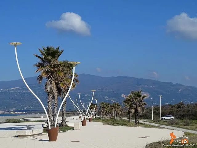 Passeggiata sul lungomare con palme e vista sui monti