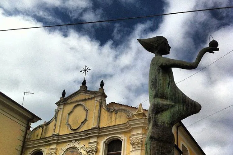 Statua femminile vista di profilo davanti a una chiesa