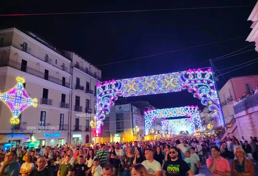 Grande folla nel centro città sotto le luminarie della festa