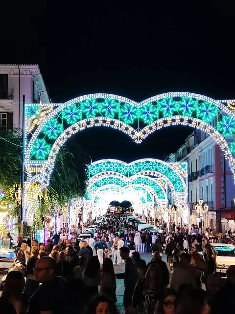 Archi luminosi e visitatori lungo una via festiva di Lamezia
