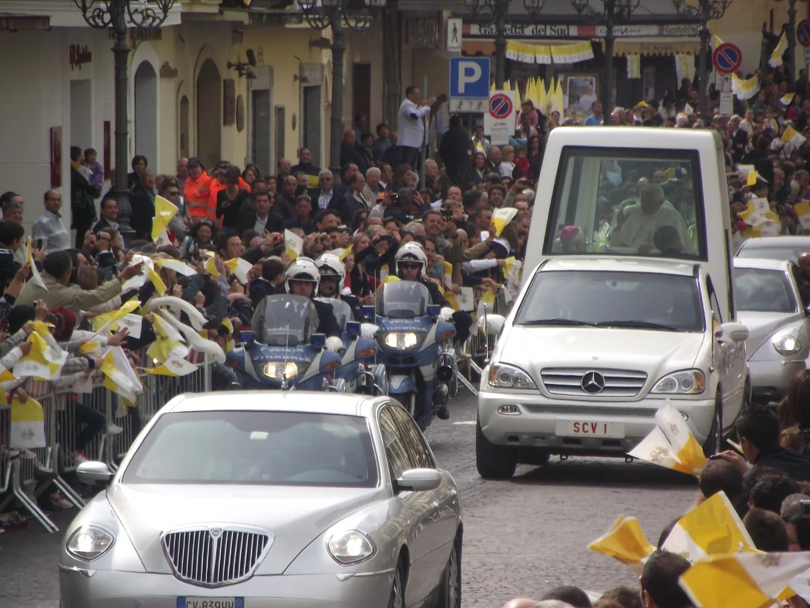 Corteo religioso con veicolo papale circondato dalla folla
